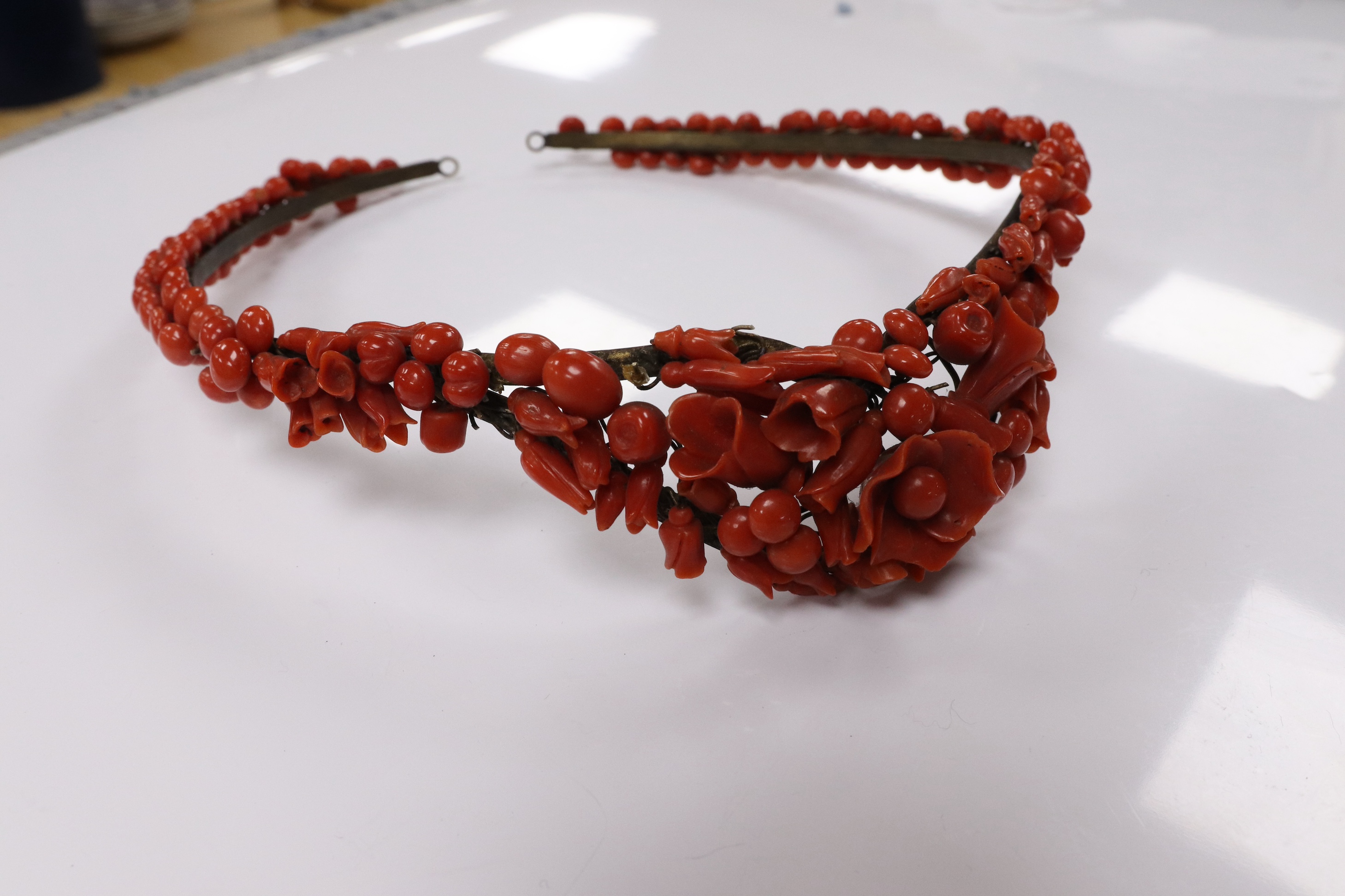 A 19th century base metal and coral bead floral designed tiara, approximately 40cm. Condition - poor to fair (some coral detached pieces in a small bag)